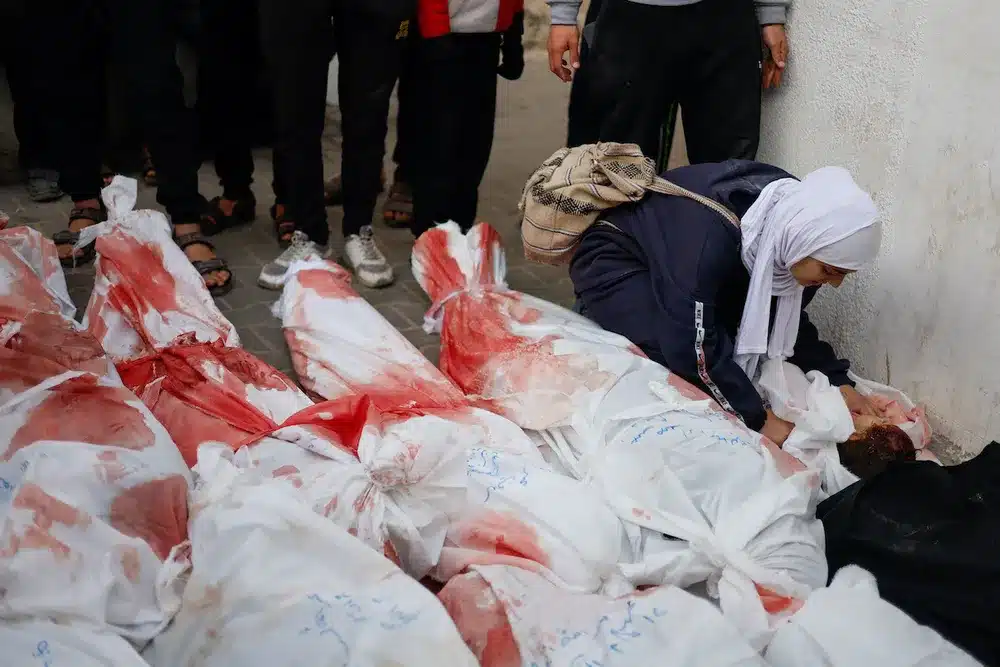 Seorang wanita berduka di samping jenazah anak-anak yang tewas dalam serangan penjajah Israel di Rafah. / Muhammad Salem (Reuters)